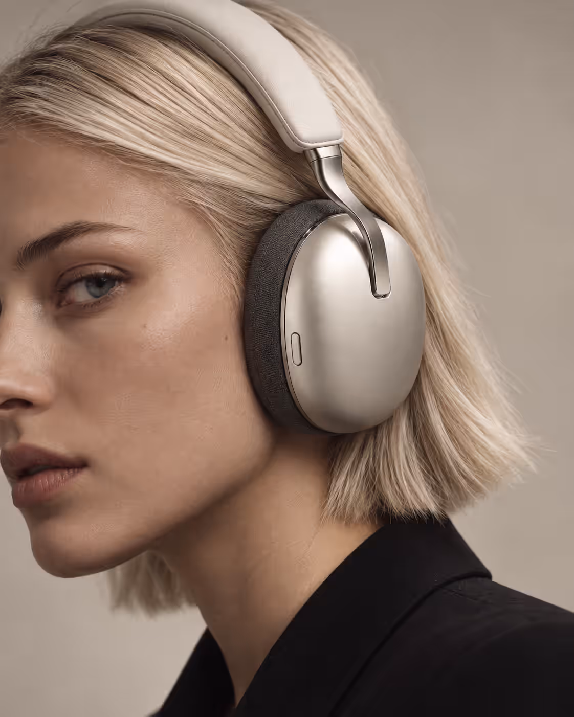 A close crop of the headphones’ brushed metal ear cup and fabric cushion on a blonde woman