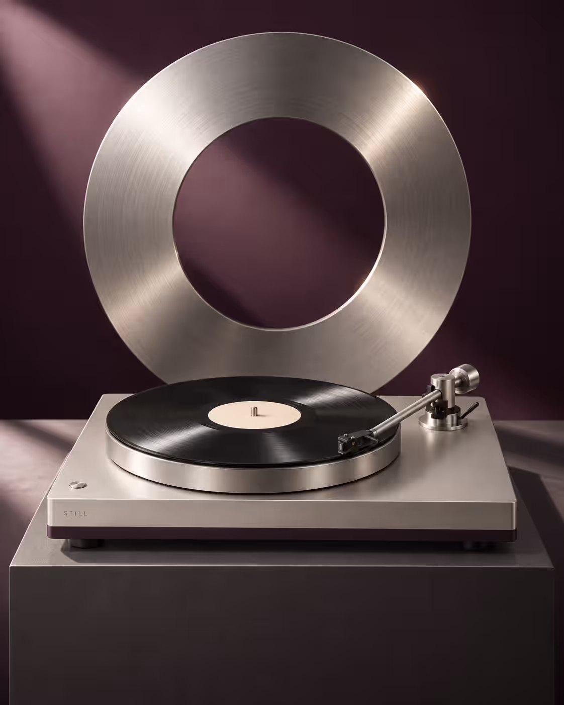 The turntable on a dark plinth in front of a large brushed metal ring
